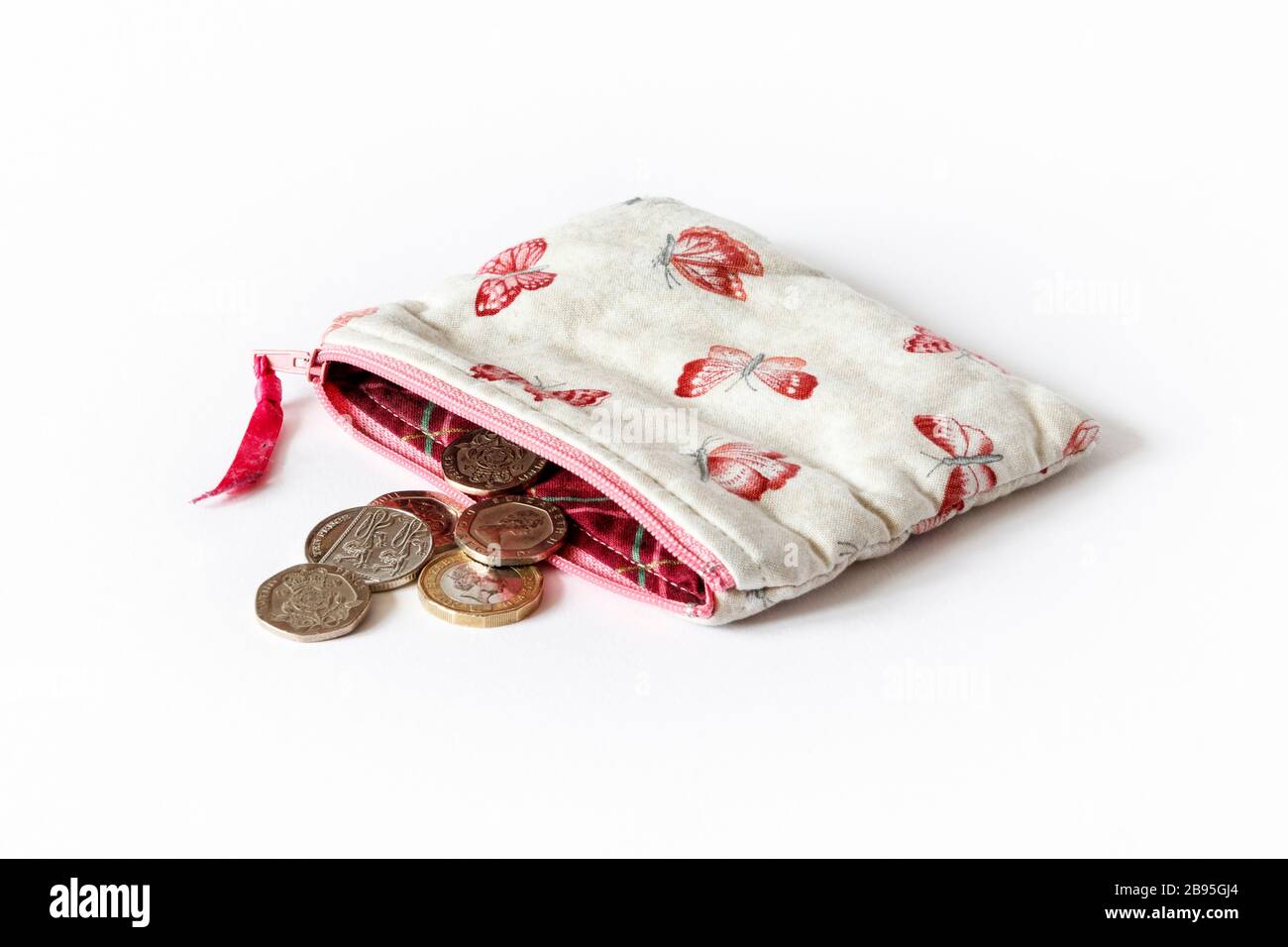 Un sac à main en tissu rose à motif papillons et fermeture à glissière ouvert avec pièces britanniques Banque D'Images