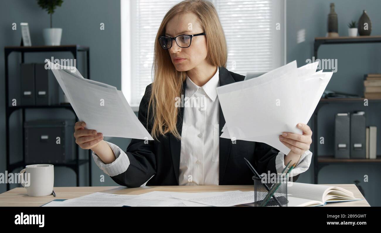 Femme d'affaires tenant des tas de papiers Banque D'Images