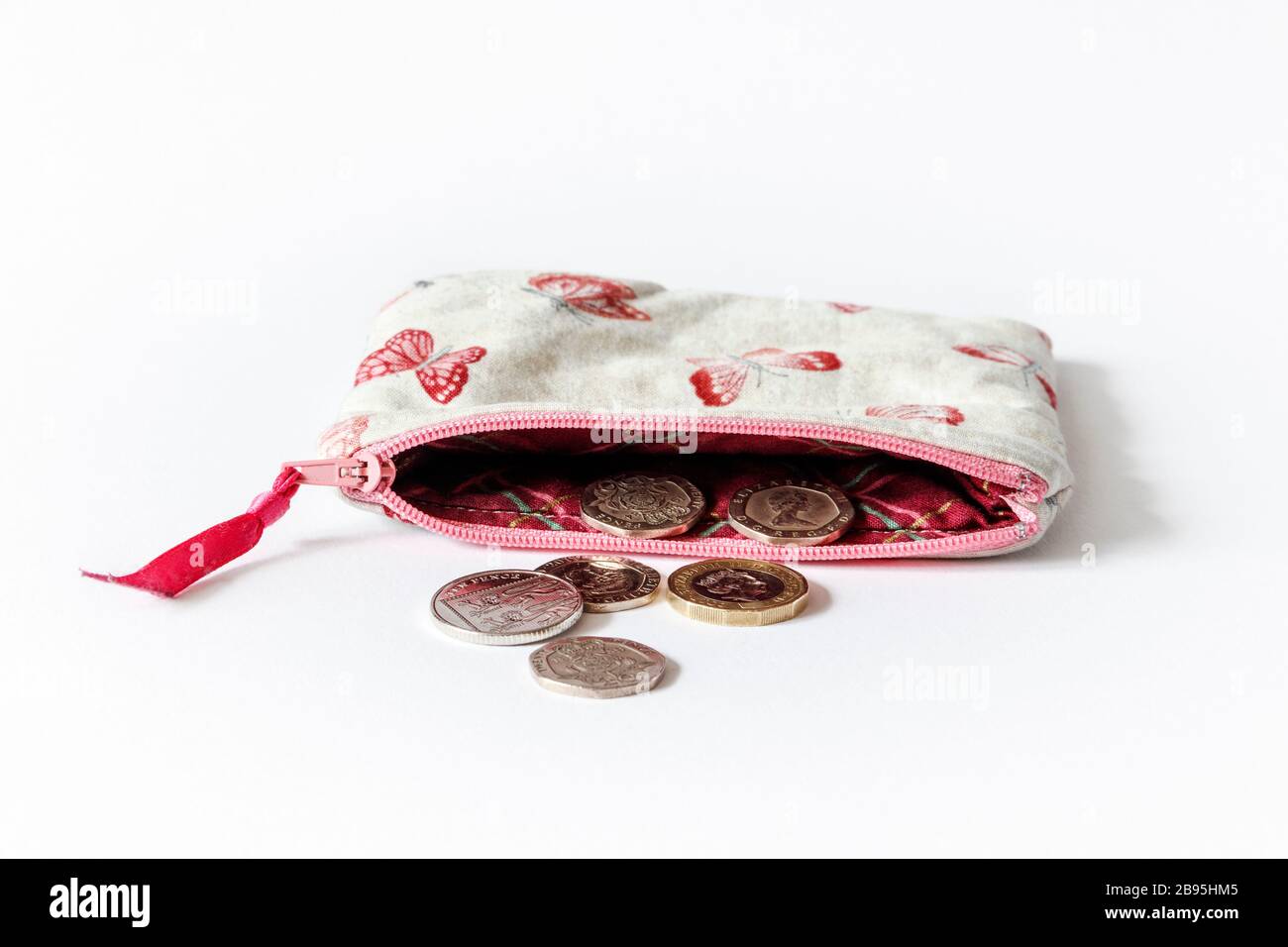 Un sac à main en tissu rose à motif papillons et fermeture à glissière ouvert avec pièces britanniques Banque D'Images