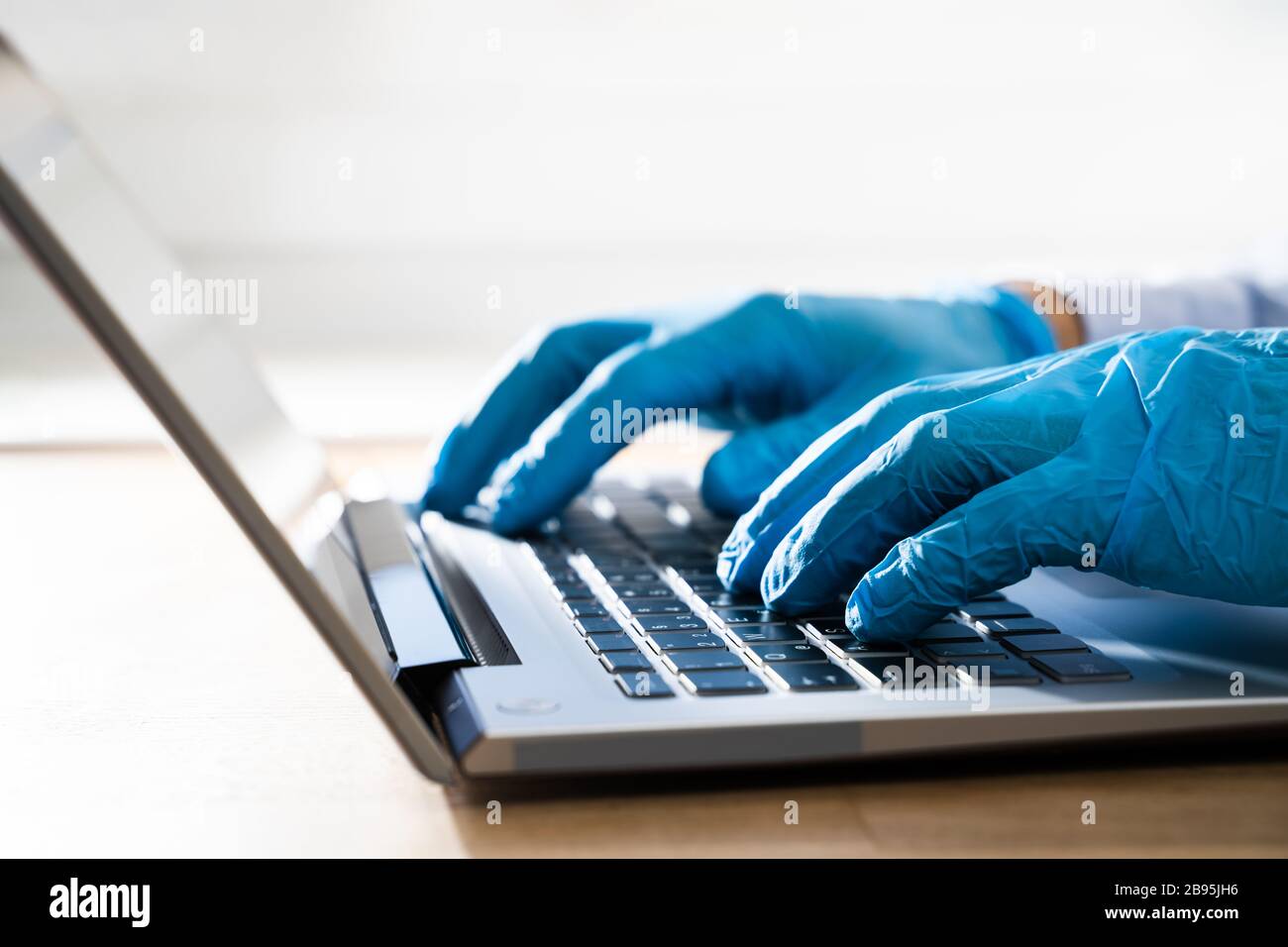 Homme en gants protégeant contre le typage de Coronavirus sur ordinateur en quarantaine à la maison Banque D'Images