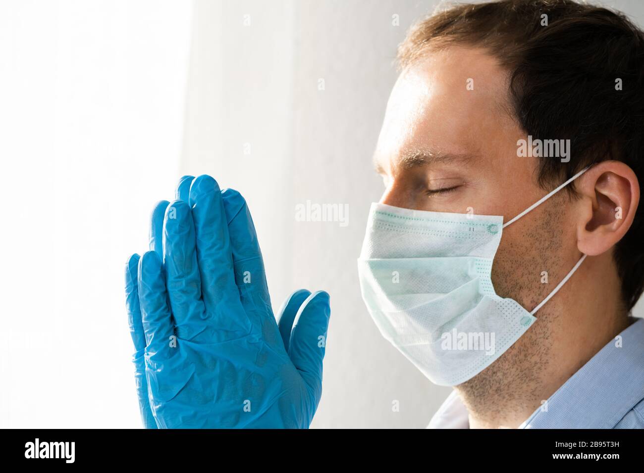 Homme en gants et masque priant pendant une pandémie de coronavirus Banque D'Images
