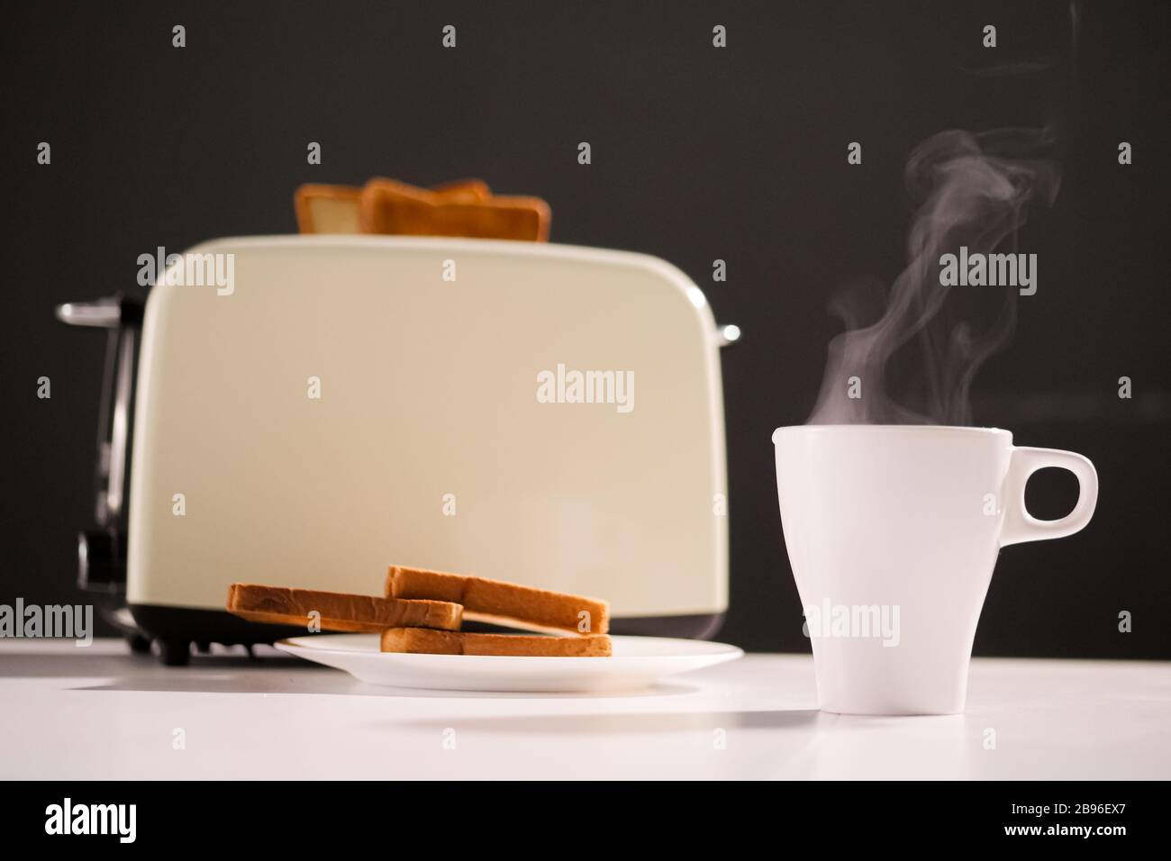 café chaud ou thé et grille-pain avec une délicieuse tranche de pain grillé sur la table de cuisine sur fond noir. Petit-déjeuner le matin Banque D'Images
