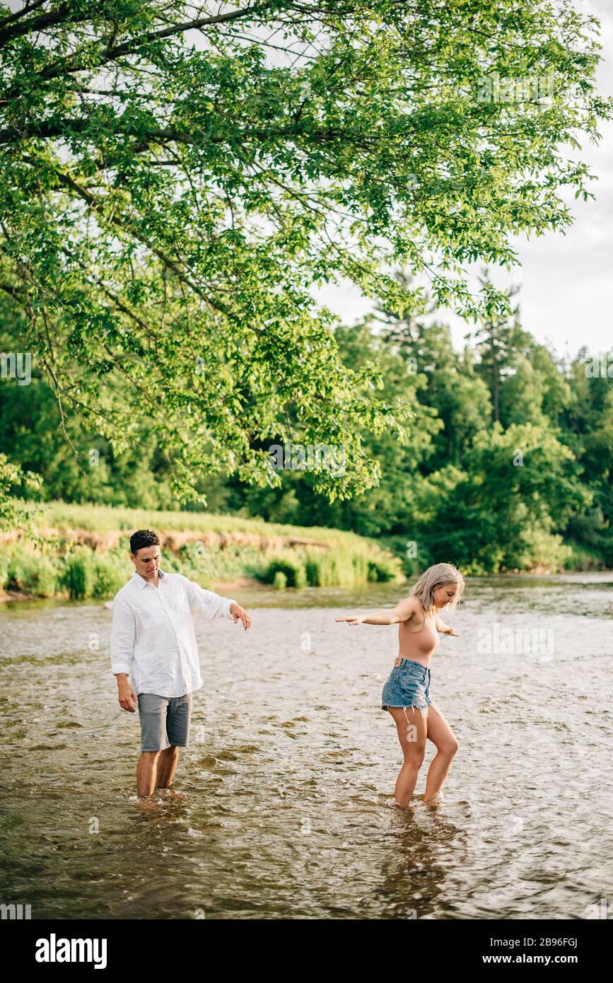 Jeune couple debout cheville profond dans une rivière. Banque D'Images