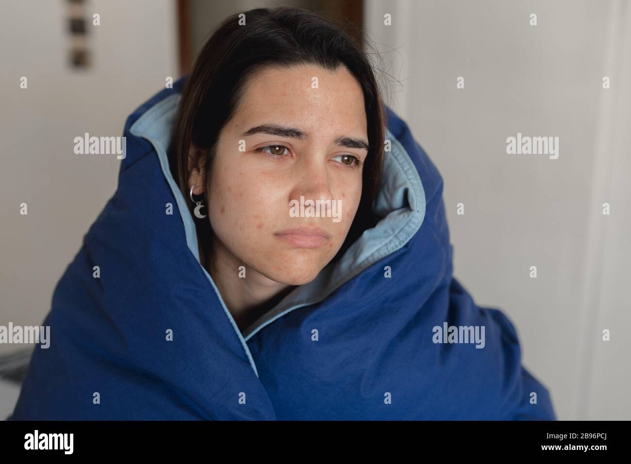 Jeune femme malade infectée par le coronavirus restant à la maison pour récupérer pendant la quarantaine en Espagne.couvrant avec une grande quilt bleu dans le monde vira Banque D'Images