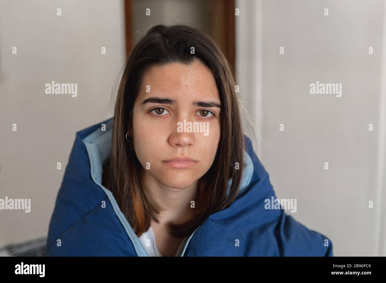 Jeune femme malade infectée par le coronavirus restant à la maison pour récupérer pendant la quarantaine en Espagne.couvrant avec une grande quilt bleu dans le monde vira Banque D'Images