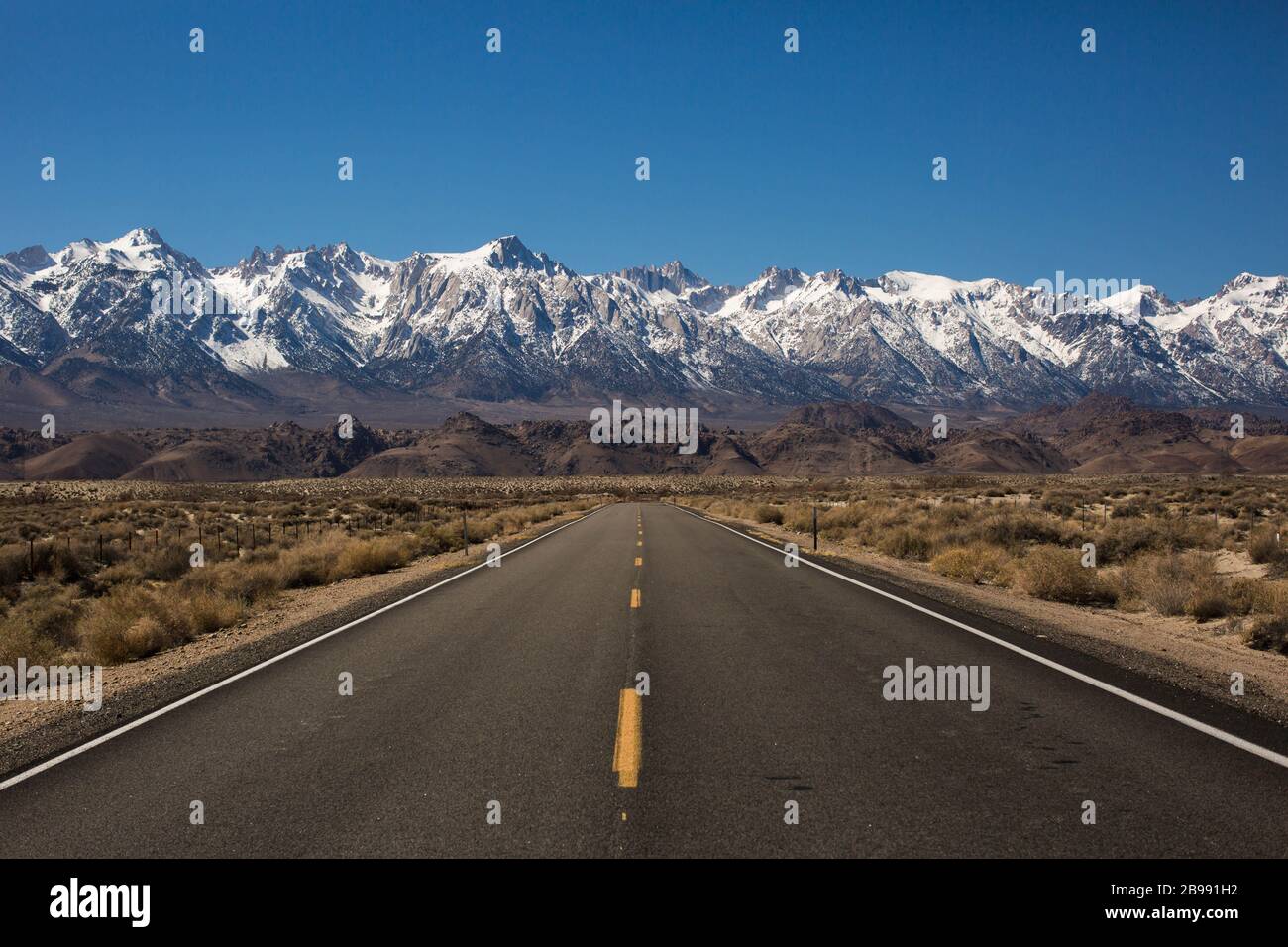 Une autoroute à la recherche infinie près du lac Owens, en Californie, disparait à l'horizon dans les montagnes de la Sierra Nevada Banque D'Images