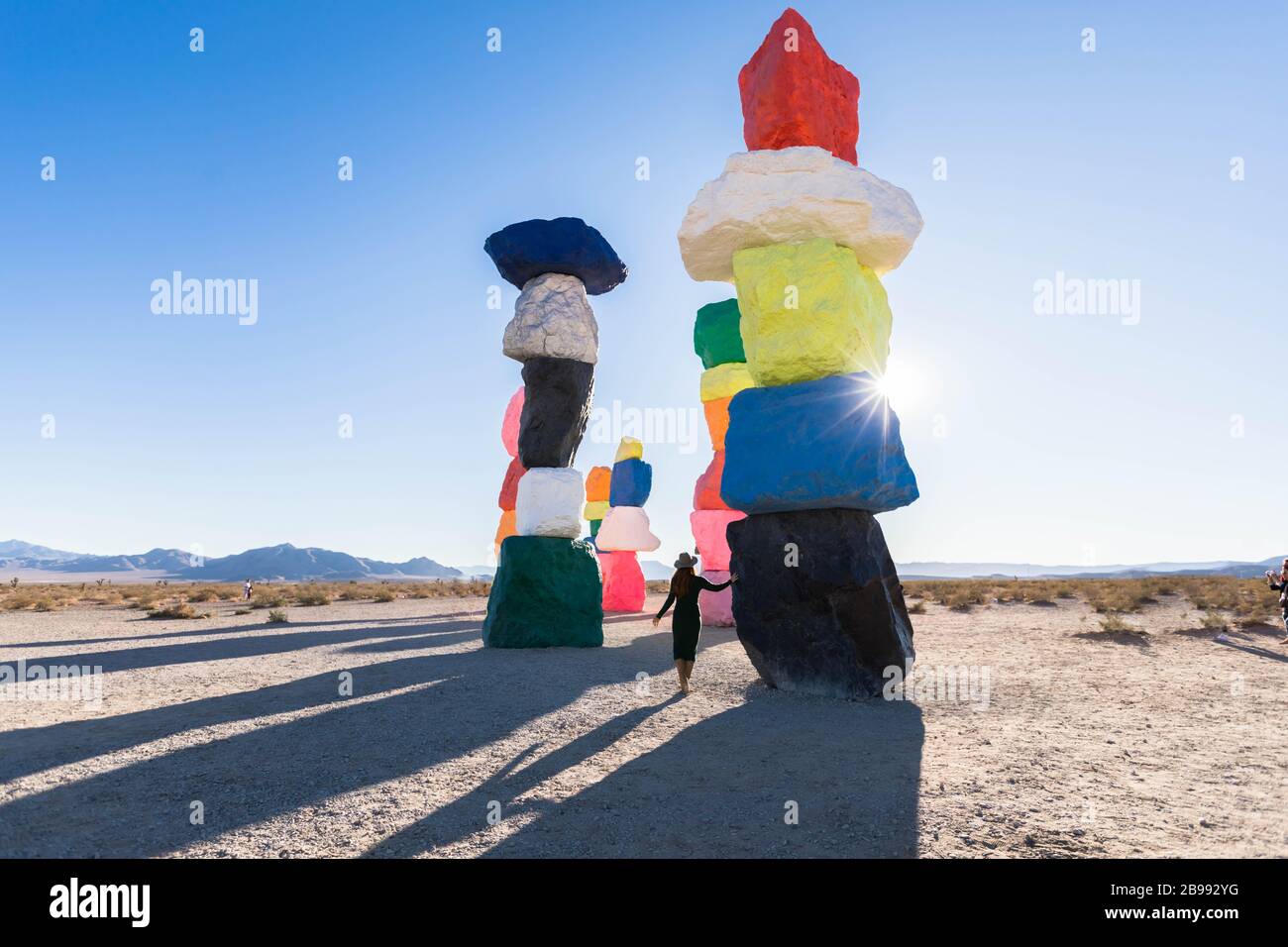 Fille avec chapeau marchant dans les sept montagnes magiques aux couleurs vives près de Las Vegas, Nevada avec soleil Banque D'Images