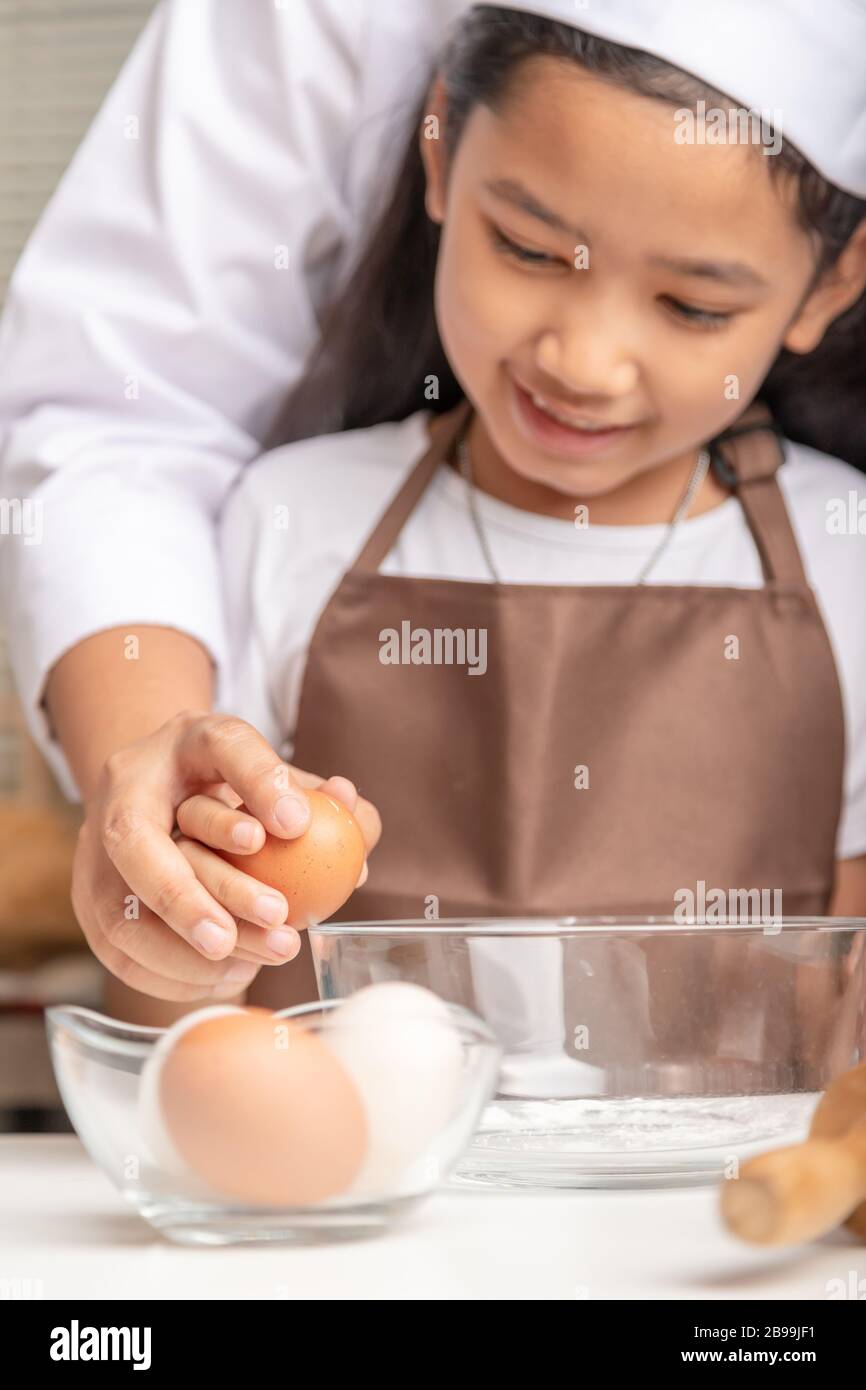 La mère enseigne à la fille à masser les œufs dans les tasses. Sélectionner la profondeur de champ faible focale de mise au point. Banque D'Images