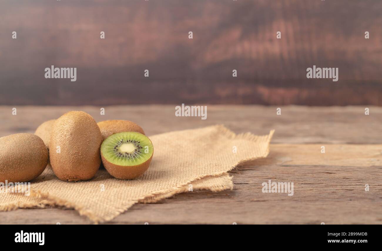 Kiwi fruits ou Actinidia chinensis et une moitié sur le sac place sur la table en bois. Banque D'Images