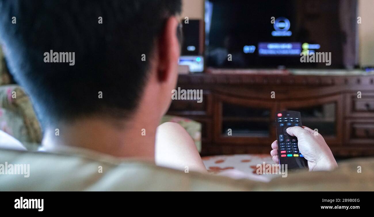 Homme regardant la télévision en se concentrant sur ses mains sur la télécommande. Divertissement à domicile ou concept de séjour à la maison. Banque D'Images