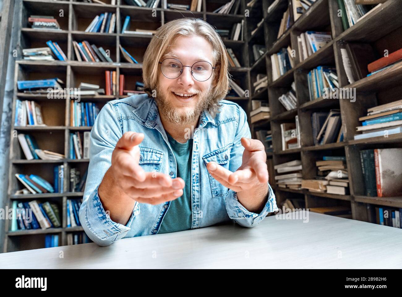 Jeune heureux barbu étudiant blogger regarder point à l'appareil photo. Banque D'Images