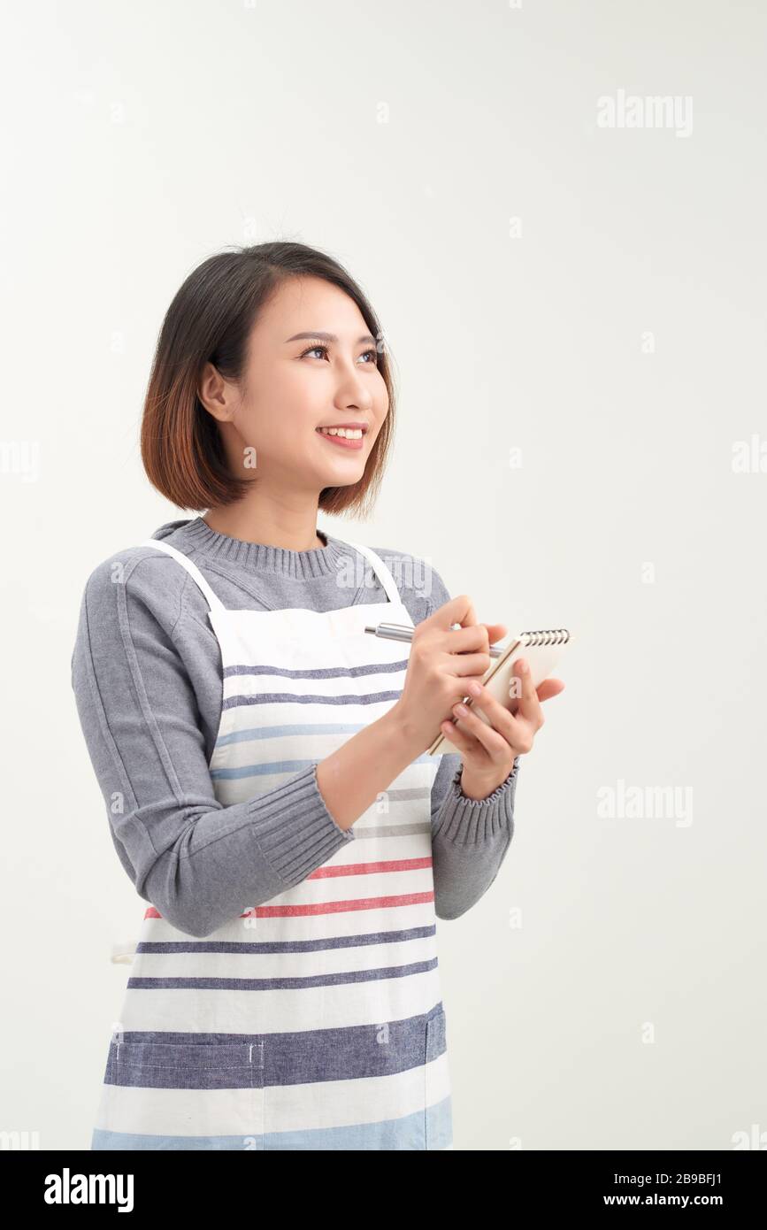 Portrait de la tête de la serveuse souriante portant un tablier noir prêt à prendre commande client, femme attrayante avec ordinateur portable et stylo dans les mains regardant CA Banque D'Images