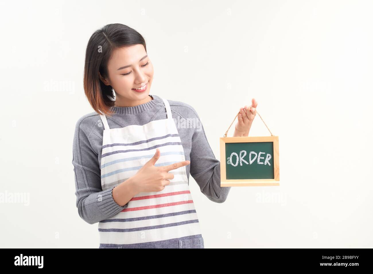 Portrait d'une serveuse souriante montrant un tableau de surveillance avec un panneau de commande en blanc Banque D'Images