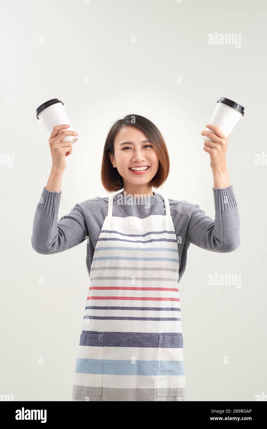 Charmante fille tient une tasse jetable avec des boissons et regarde directement à l'appareil photo isolé sur fond blanc Banque D'Images