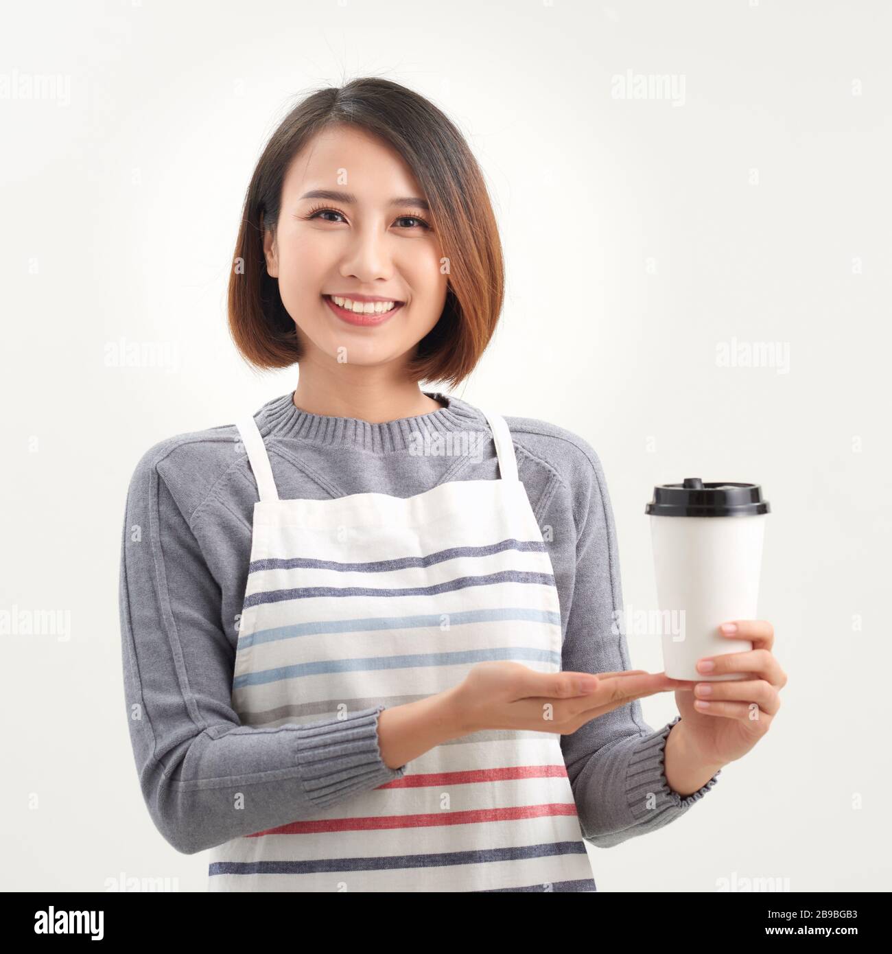 Une serveuse tenant et servant une tasse de café chaud en papier dans le café Banque D'Images