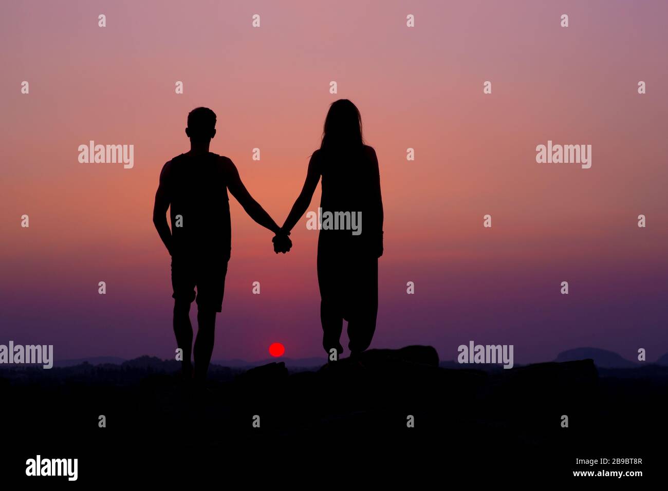 Une Silhouette d'un couple tenant les mains au coucher du soleil. Banque D'Images