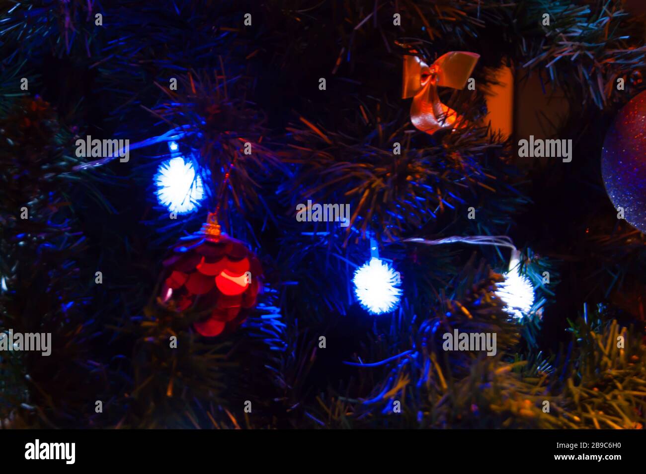 Boules et arcs rouges sur l'épicéa de Noël ou de Noël, feux bleu brillant de guirlande. Vacances bonheur cadeaux mystiques la vie de la décoration miracle de l'intérieur de la maison Banque D'Images