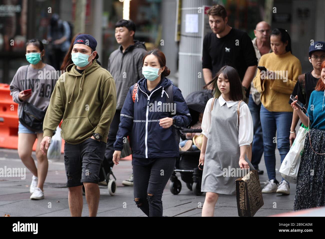 SYDNEY, AUSTRALIE, 24 mars 2020, un groupe de personnes portant un masque chirurgical est vu dans les rues de la CDB de Sydney suite à la réponse du gouvernement à l’épidémie de coronavirus à la fermeture d’entreprises non essentielles et à la limitation du contact physique entre les personnes. Crédit: Sebastian Reategui/Alay Live News Banque D'Images