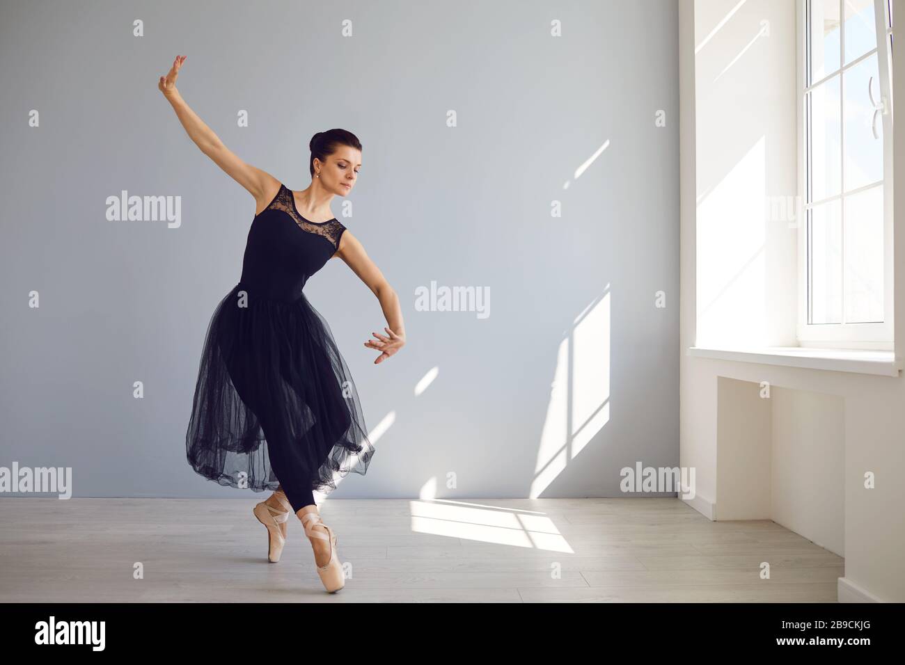 Ballerina posant dans un studio lumineux avec fenêtres. Banque D'Images