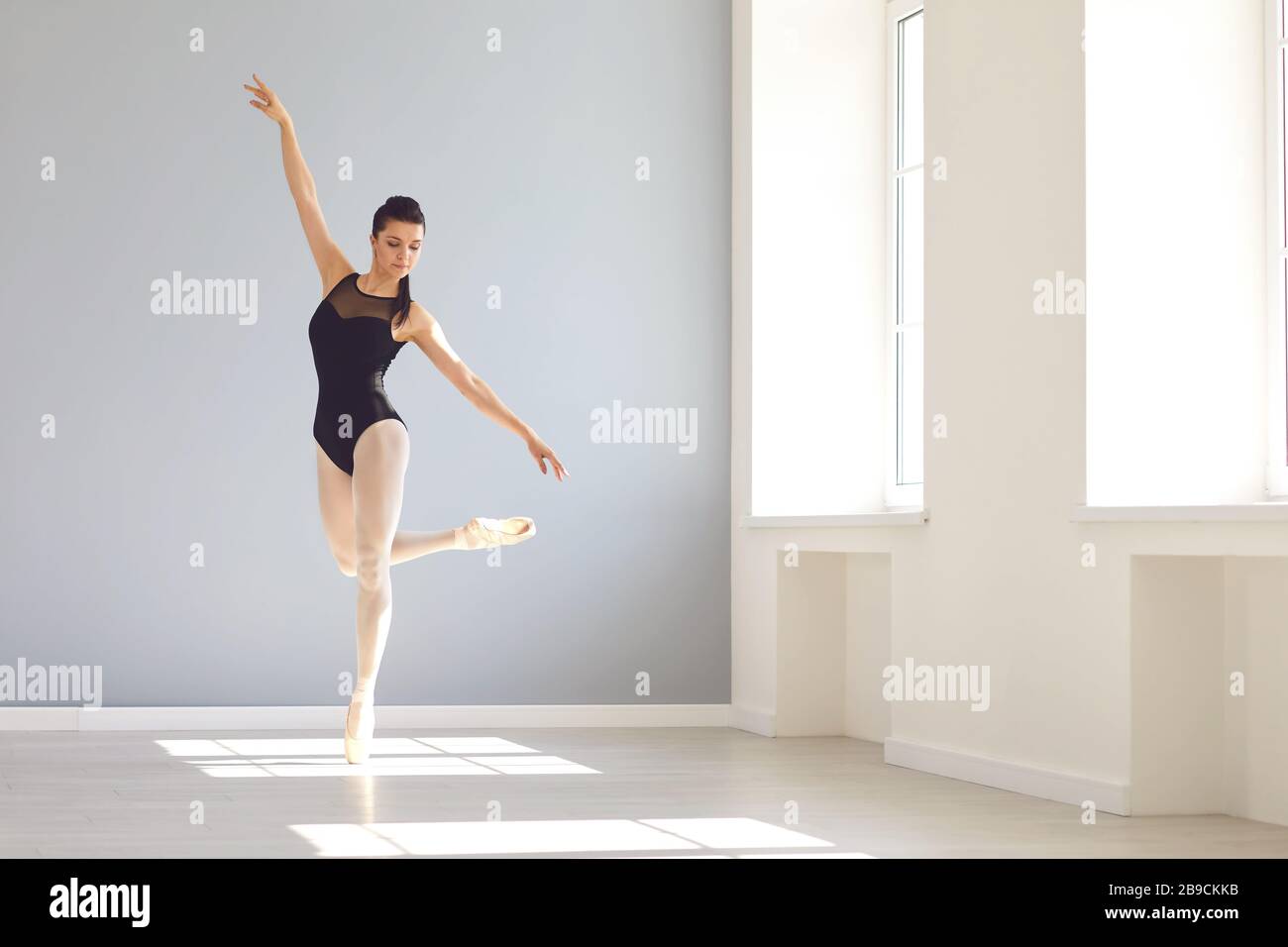 Ballerina posant dans un studio lumineux avec fenêtres. Banque D'Images