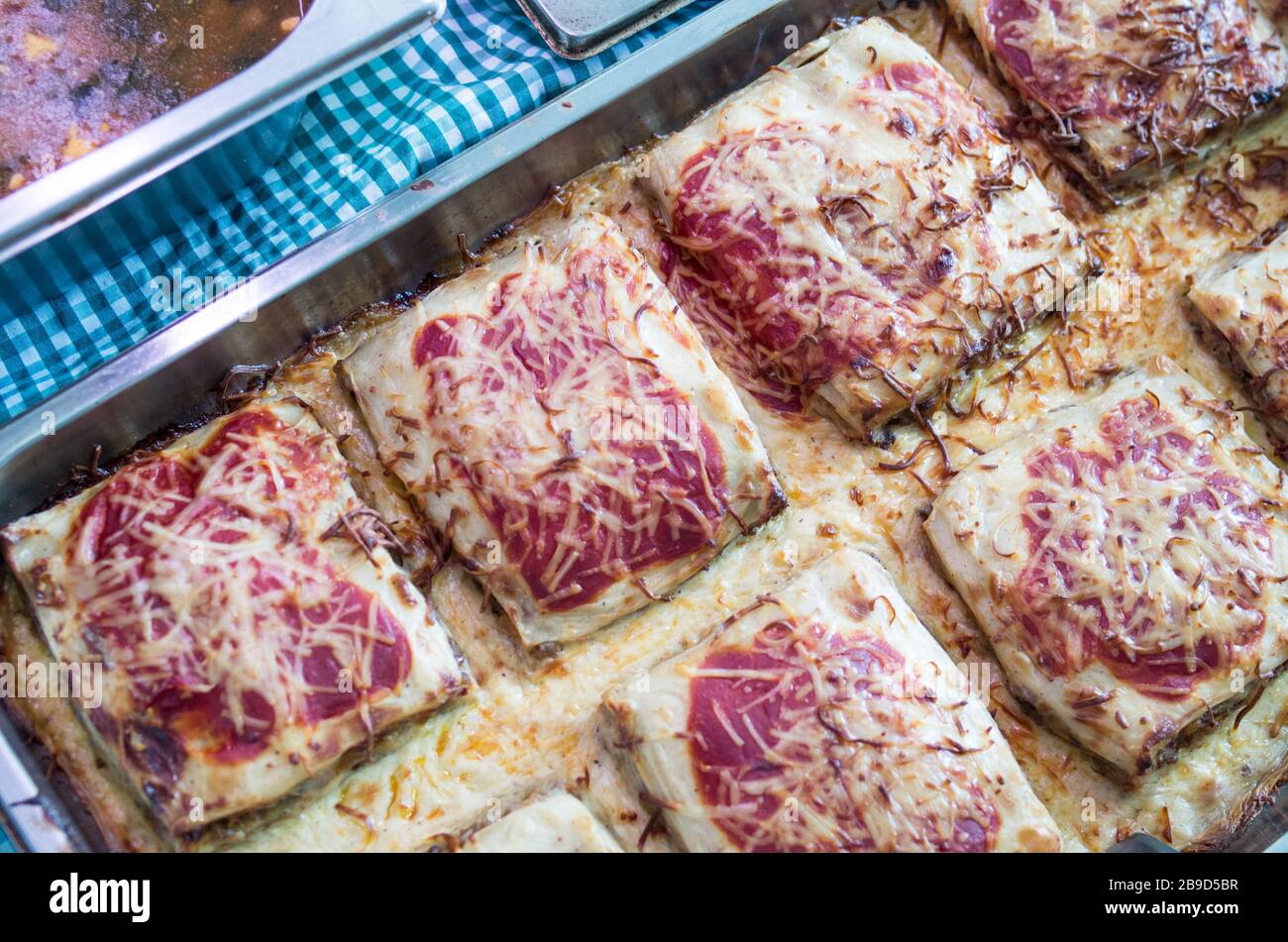 Les Cannelloni farci aux épinards et poivron rouge rôti et différents fromages fondus dans un plateau en aluminium pour le libre-service ou des plats à emporter servi dans Banque D'Images