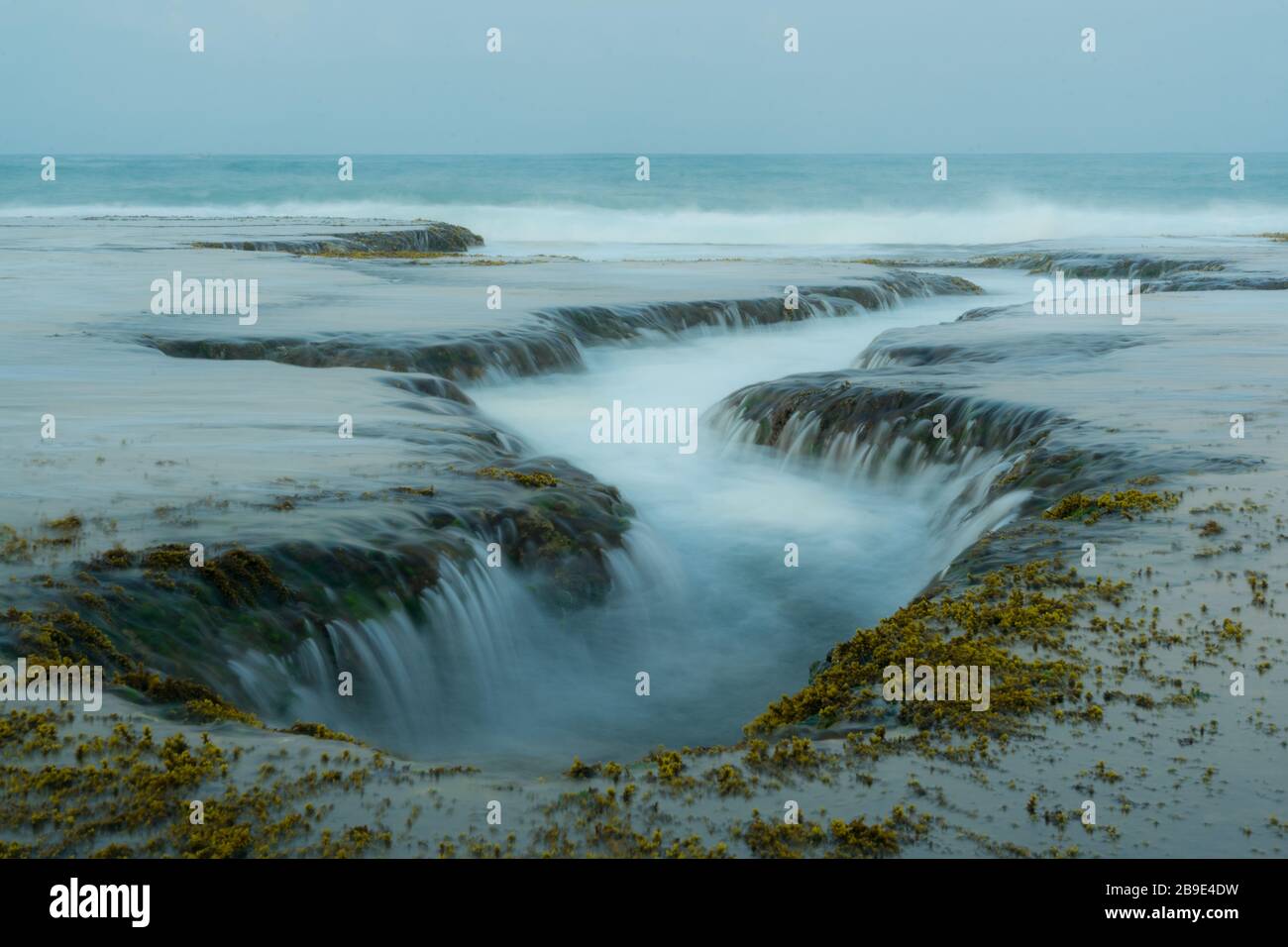 L'eau de l'océan unique coule à travers le phénomène des roches comme une chute d'eau. Emplacement idéal pour les photographes près de Sawarna, province de Banten, Java, Indonésie Banque D'Images