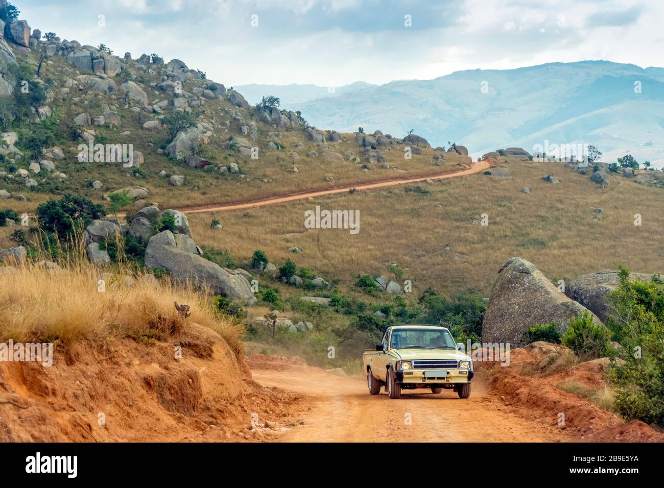 Voiture ancienne conduite sur route rouge, terre dans un paysage incroyable d'Eswatini Banque D'Images