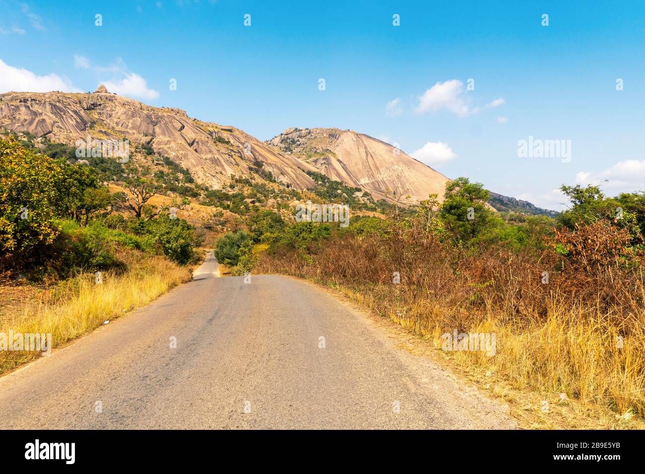 Route au pied d'un énorme rocher monolithe appelé Sibebe à côté de Mbabane, capitale d'Eswatini Banque D'Images