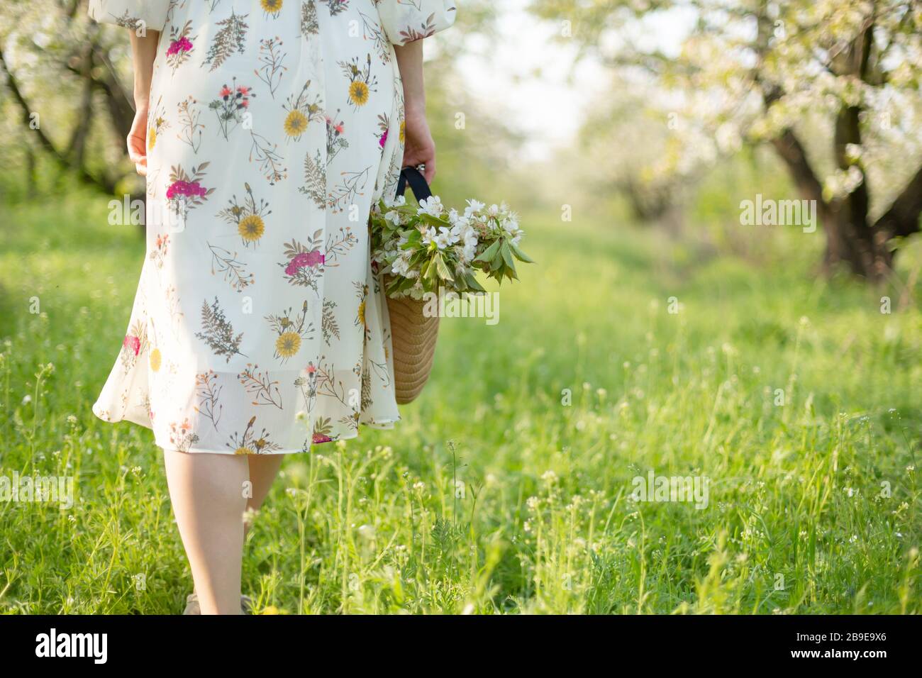 Une fille marche dans un parc vert printemps profiter de la nature en fleurs. Banque D'Images