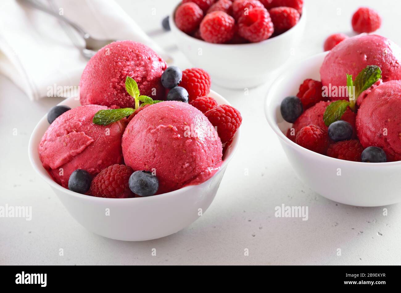 Pelle à glace aux framboises avec framboises fraîches et bleuets dans un bol sur fond de pierre. Dessert d'été froid. Banque D'Images