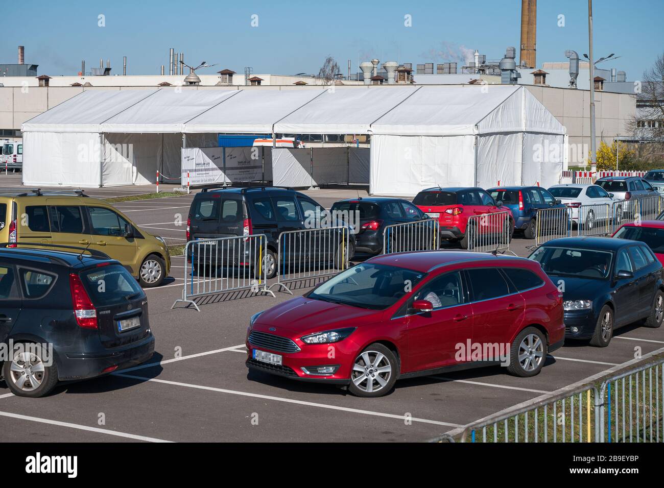 24 mars 2020, Sarre, Saarlouis : une file d'attente de voitures s'est  formée devant une station d'essai au volant dans le parking de l'usine Ford  de Saarlouis. Le Covid-19 Drive in Test