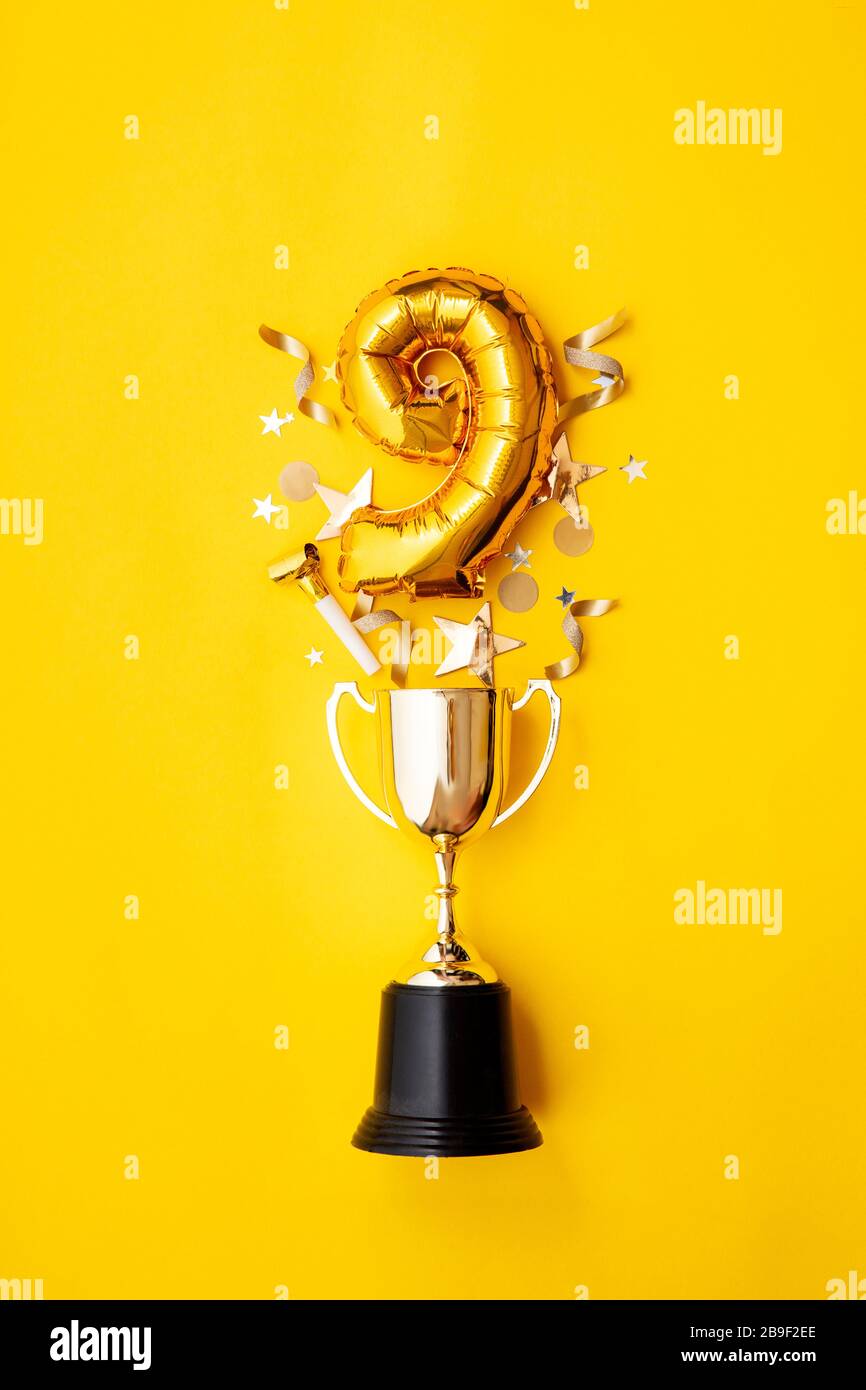 Le ballon numéro 9 de célébration de l'anniversaire de l'or explose à partir d'un trophée gagnant Banque D'Images