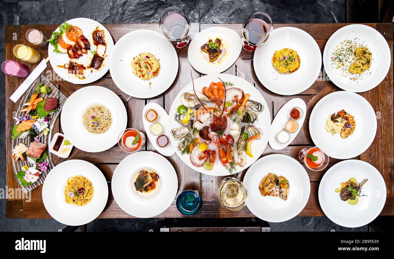 Vue sur le plan de table variété de plats internationaux de qualité dans le restaurant de crevettes de homard steak boeuf agneau pâtes spaghetti risotto riz sushi sashimi et wi Banque D'Images