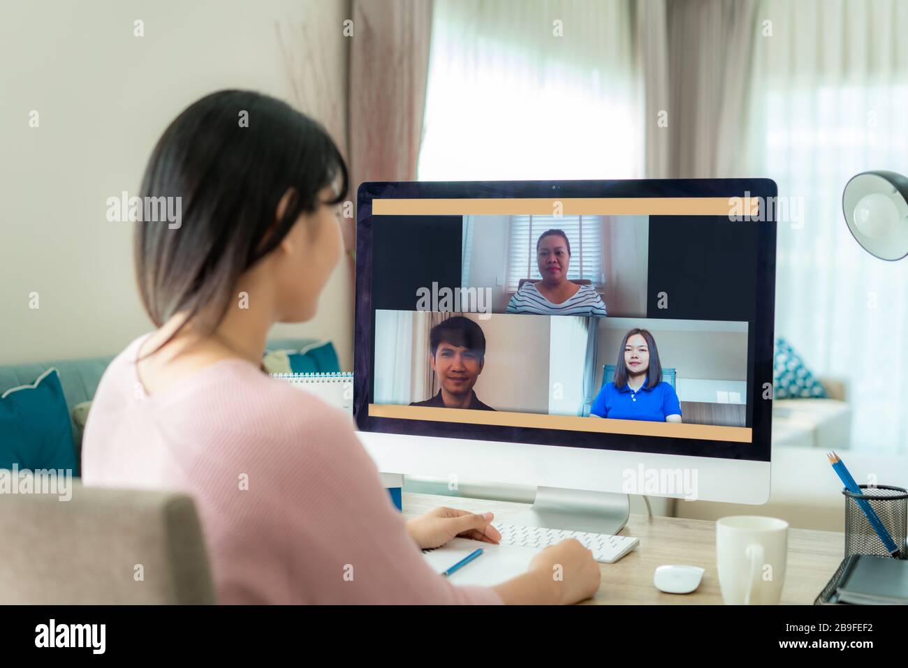 Vue arrière de la femme d'affaires asiatique parlant à ses collègues du plan dans la vidéoconférence. Équipe d'affaires multiethnique utilisant l'ordinateur pour une rencontre en ligne Banque D'Images