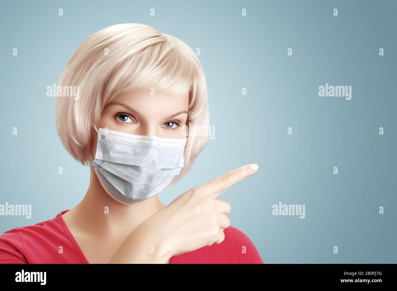 Jolie jeune fille avec cheveux blond dans un masque médical protecteur pointe un doigt à l'espace de copie. Modèle de bannière médicale. Banque D'Images