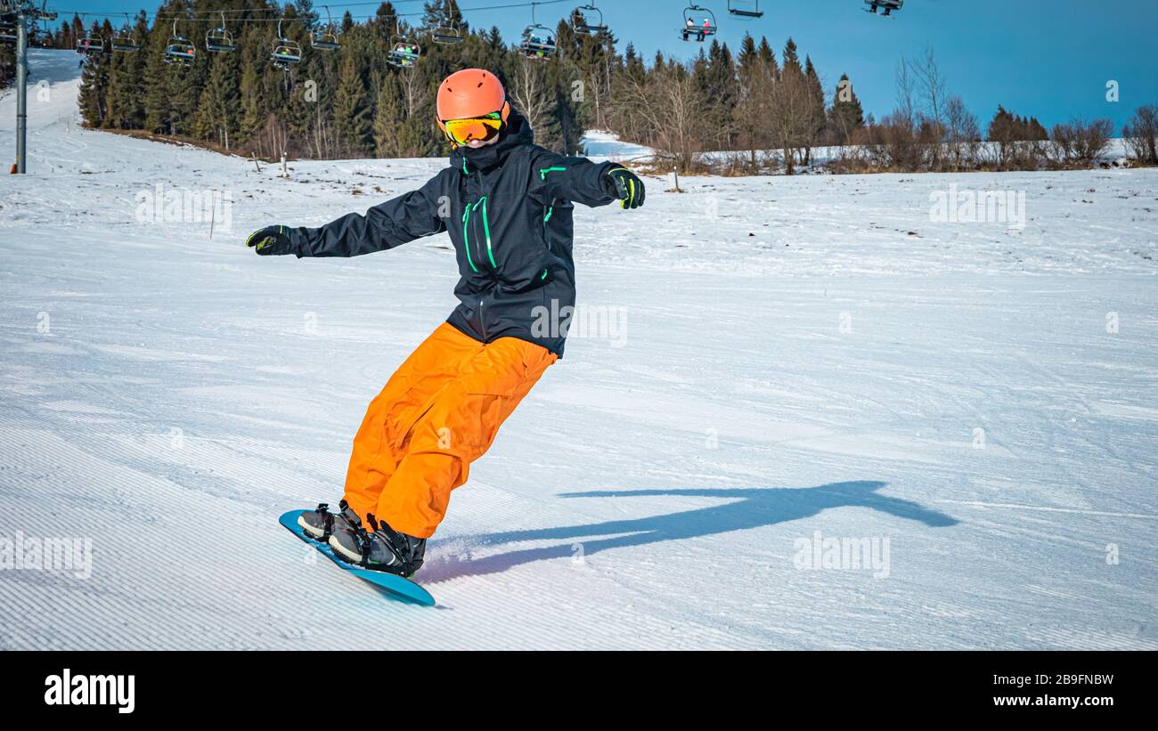 Homme adolescent prenant un tour avec son snowboard sur un jour nuageux Banque D'Images