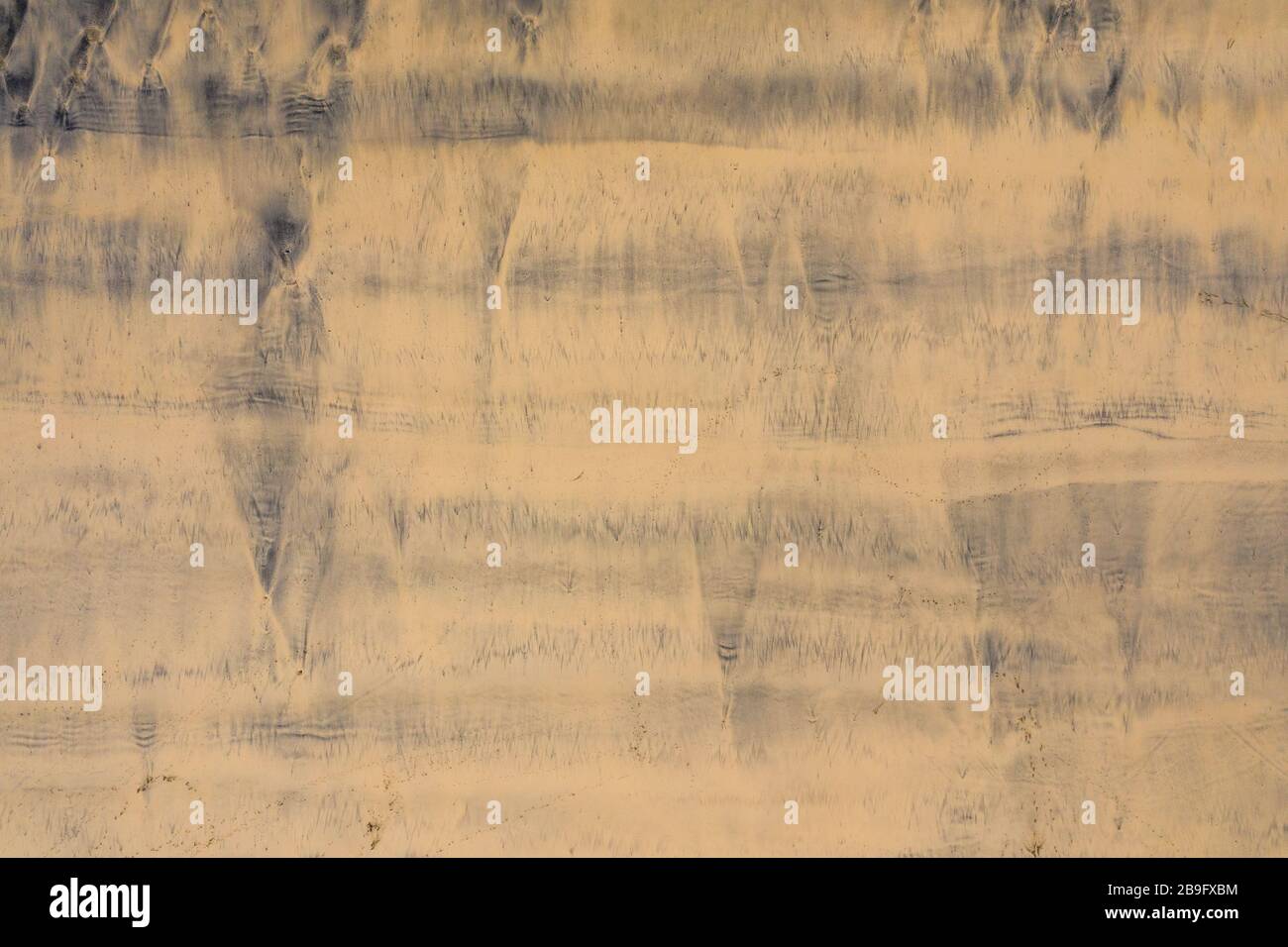 photo aérienne des motifs de silty sombre laissés dans le sable doré par la marée Banque D'Images