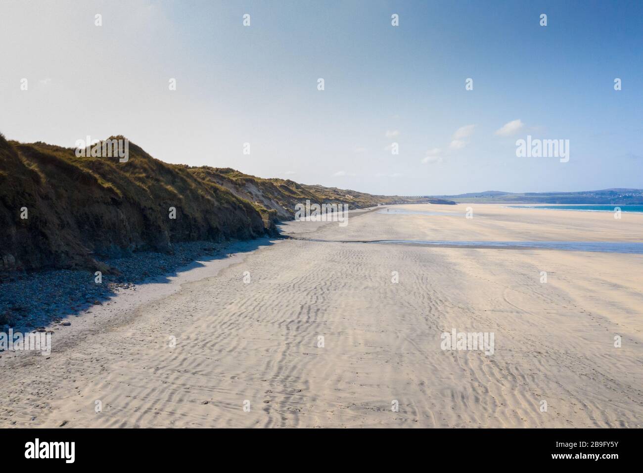 Photo aérienne d'une plage de Gwithian vide avec vagues déferlantes et dunes de sable sur une journée de ciel bleu Banque D'Images