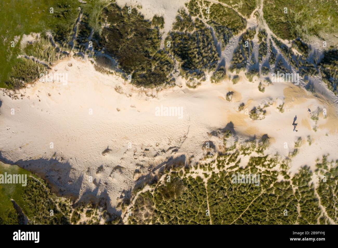 Image aérienne d'une grande dune de sable avec de l'herbe naturelle et 2 personnes debout au sommet Banque D'Images