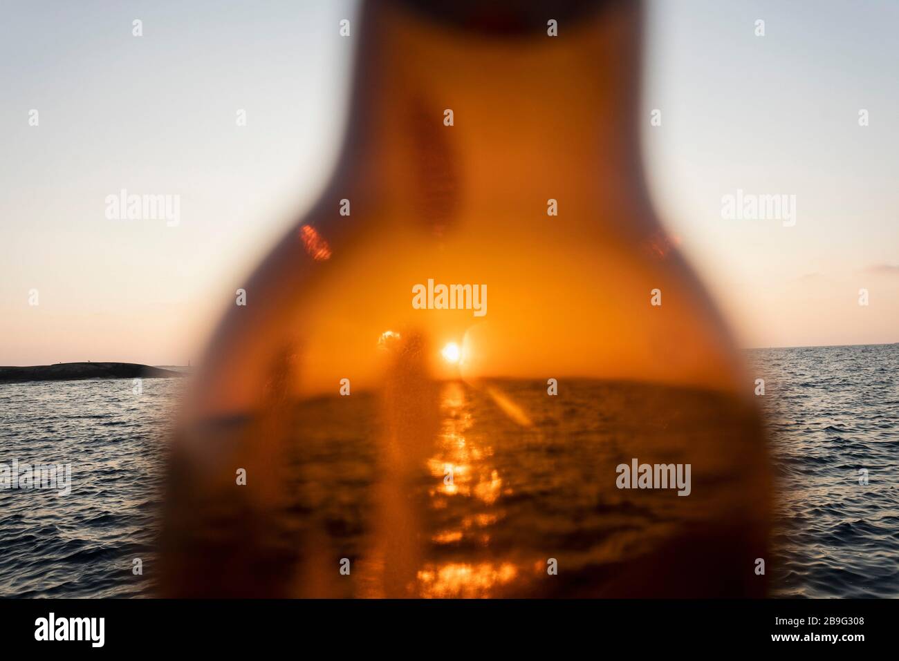 Coucher de soleil sur l'océan à travers la bouteille de bière en verre brun Banque D'Images