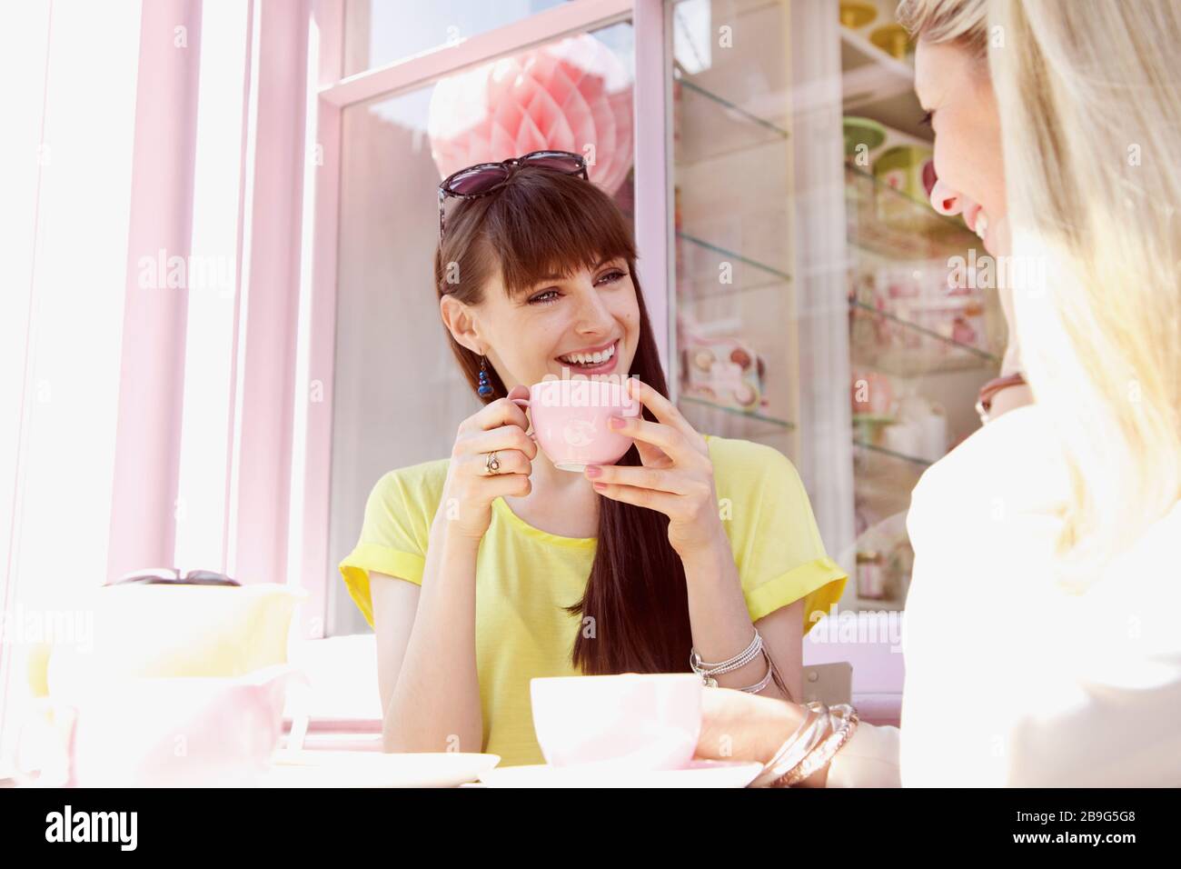De jeunes femmes amies heureux boire du café dans un café ensoleillé Banque D'Images