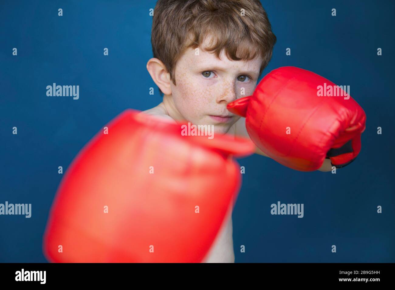 Portez un garçon résistant avec des gants de boxe pour lutter contre la position Banque D'Images