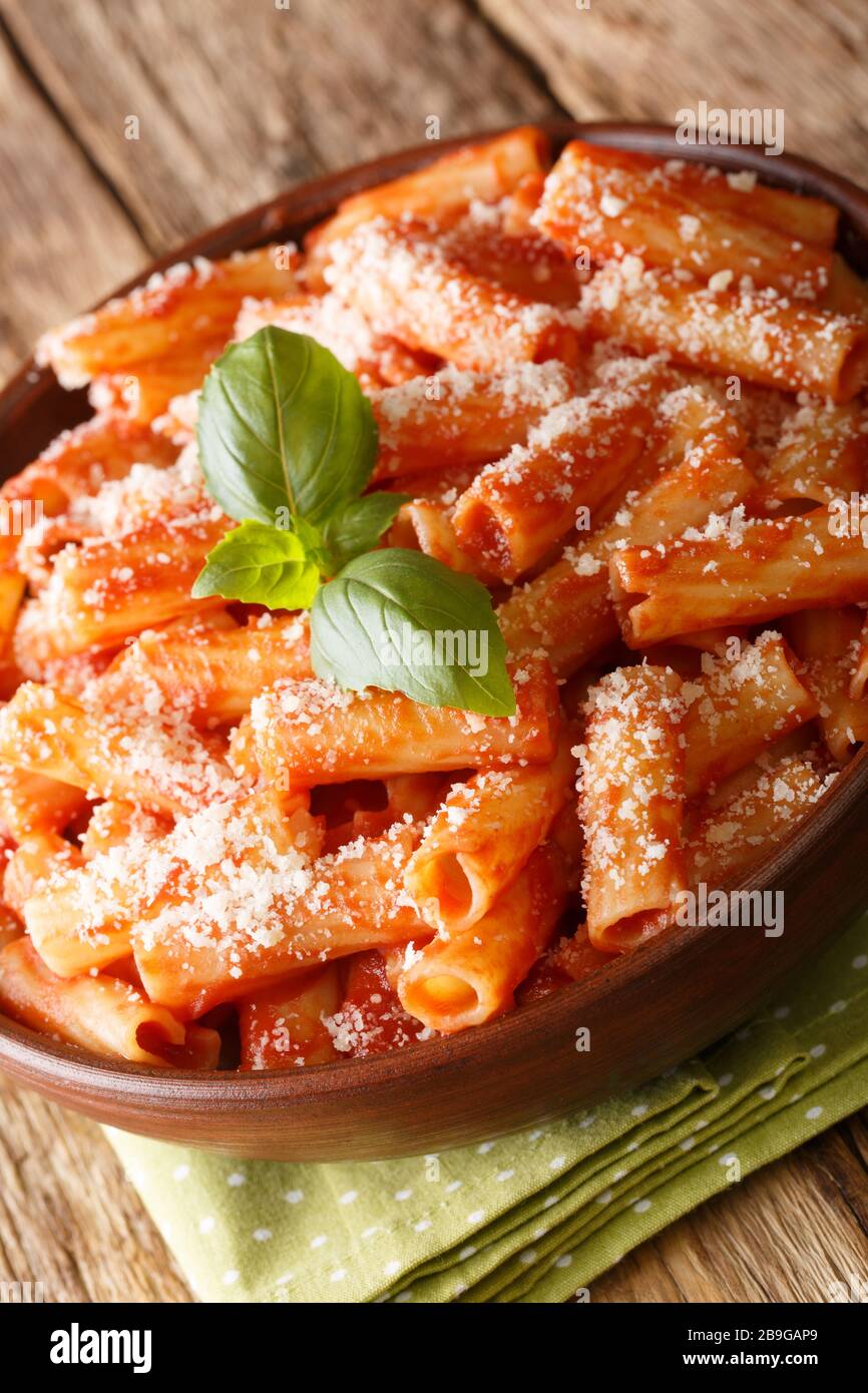 Pâtes Tortiglioni au basilic parmesan dans la sauce tomate, gros plan dans une assiette sur la table. Verticale Banque D'Images