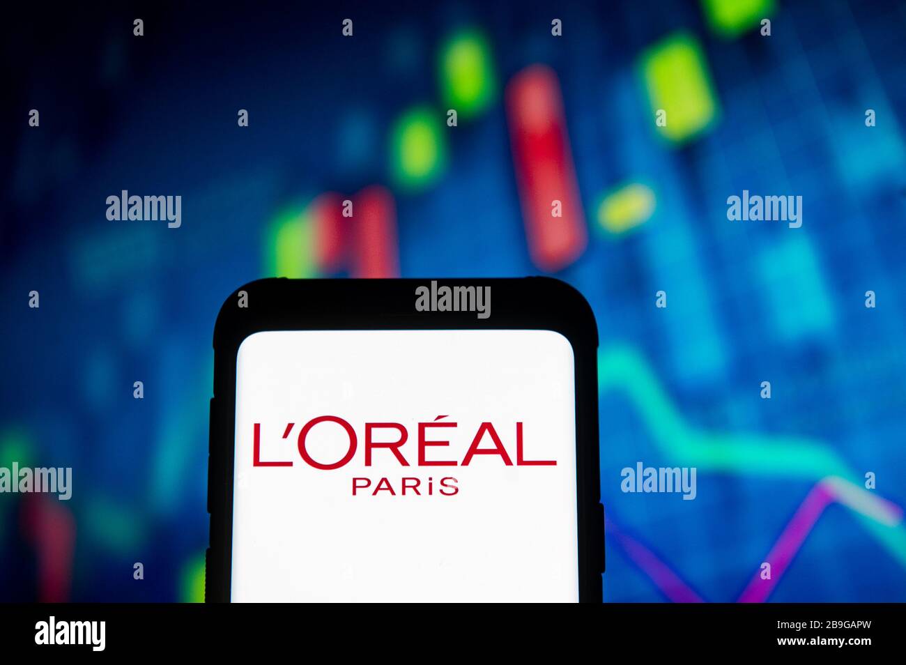 Dans cette illustration photo, un logo l'oreal Paris apparaît sur un smartphone.une carte de la bourse est affichée en arrière-plan. Banque D'Images