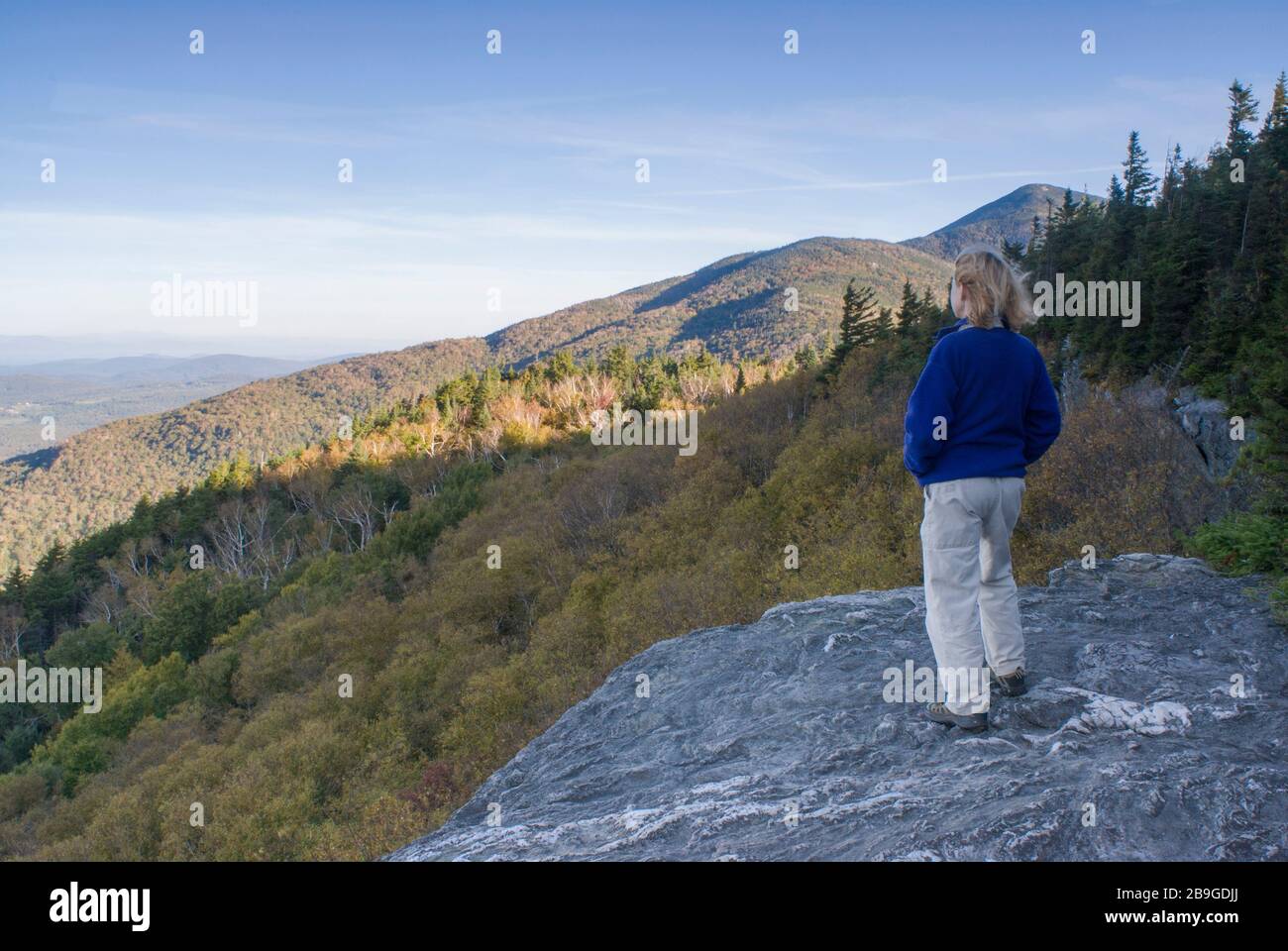 Femme portant une veste polaire en regardant la vue sur la montagne depuis la corniche de roche sur le long Trail en route jusqu'au Mt. Subvention à Lincoln, Vermont Banque D'Images