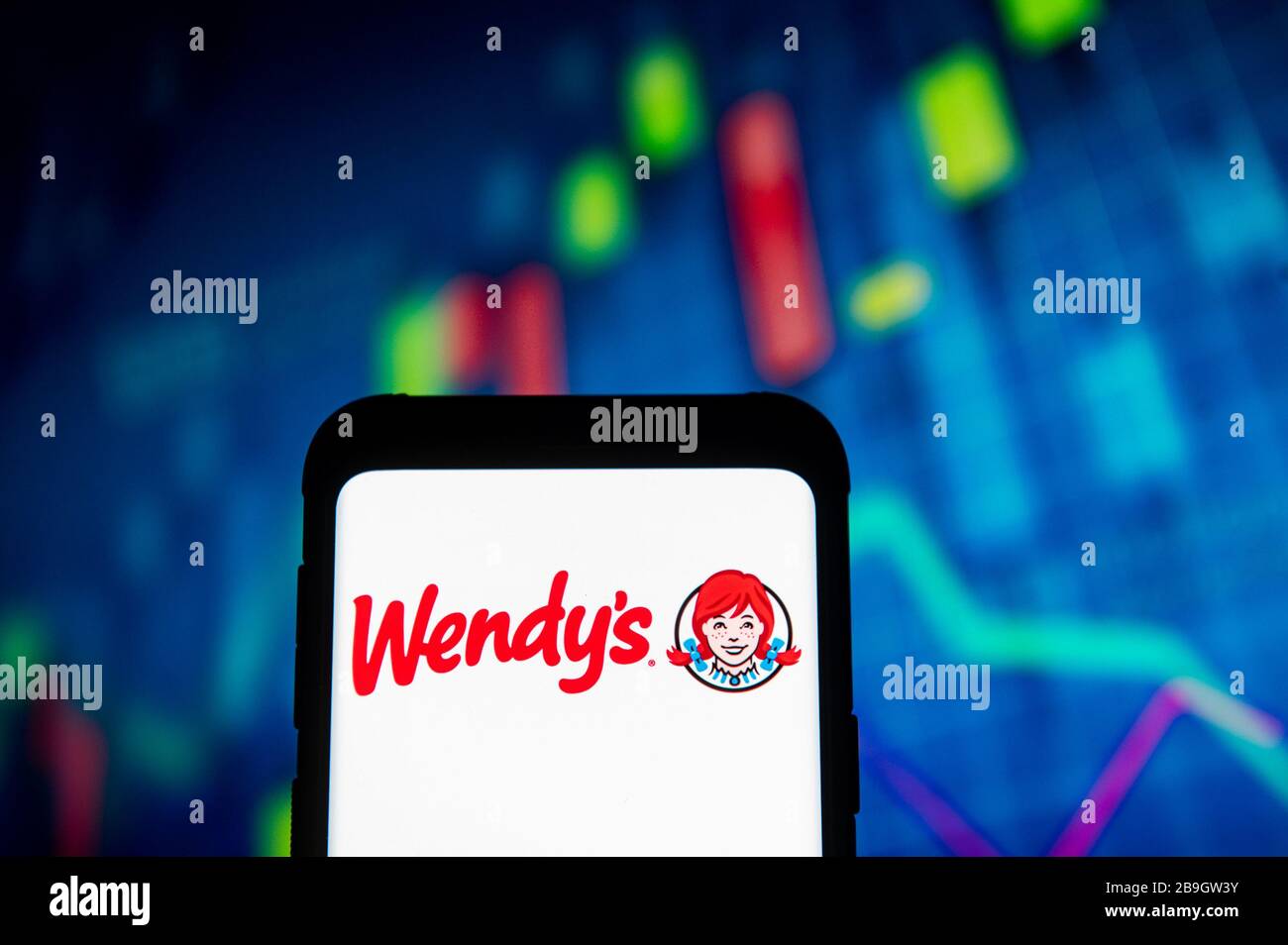 Pologne. 23 mars 2020. Dans cette illustration photo, un logo Wendys apparaît sur un smartphone.un graphique de la bourse est affiché en arrière-plan. Crédit: Mateusz Slodkowski/SOPA Images/ZUMA Wire/Alay Live News Banque D'Images