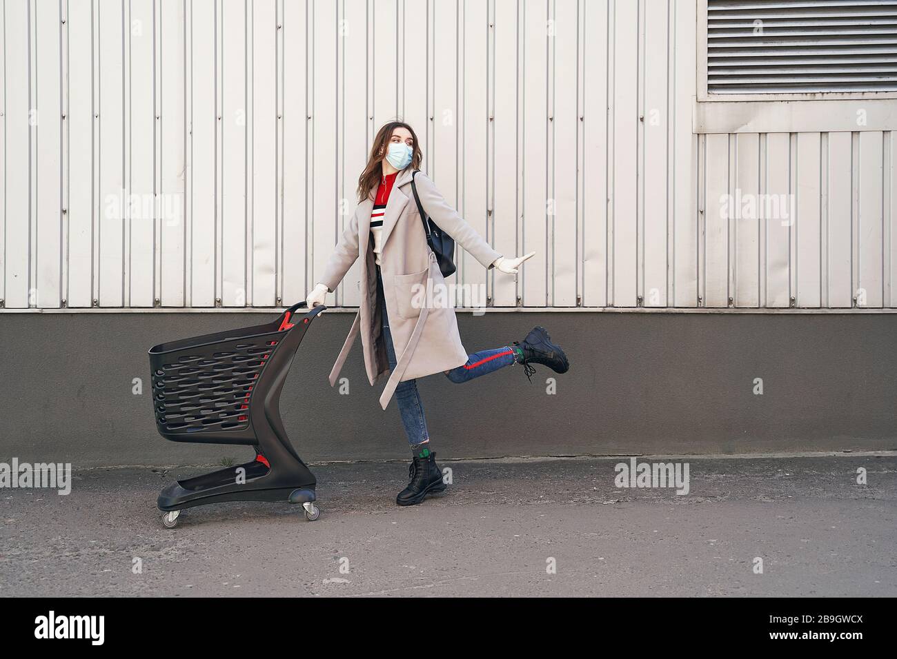 Jeune femme portant un masque de protection contre le coronavirus COVID-2019, roman coronavirus 2019-nCoV poussant un panier dans le département de supermarché Banque D'Images