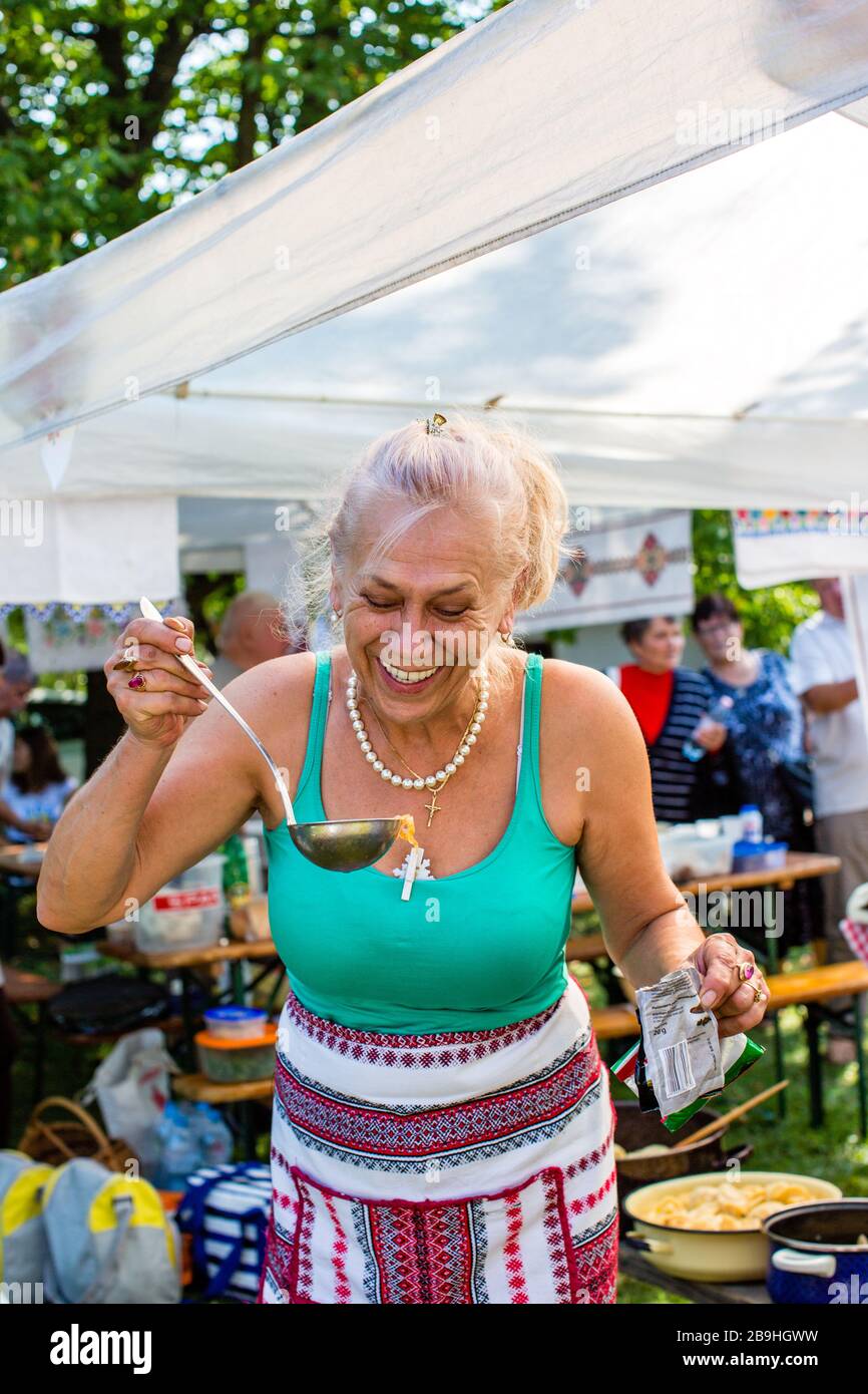 Nyiregyhaza, Hongrie - 10 septembre 2017: Une jeune femme de cuisine dans un tablier brodé a le goût de la soupe ukrainienne borscht de louche. Véritable événement et peop Banque D'Images