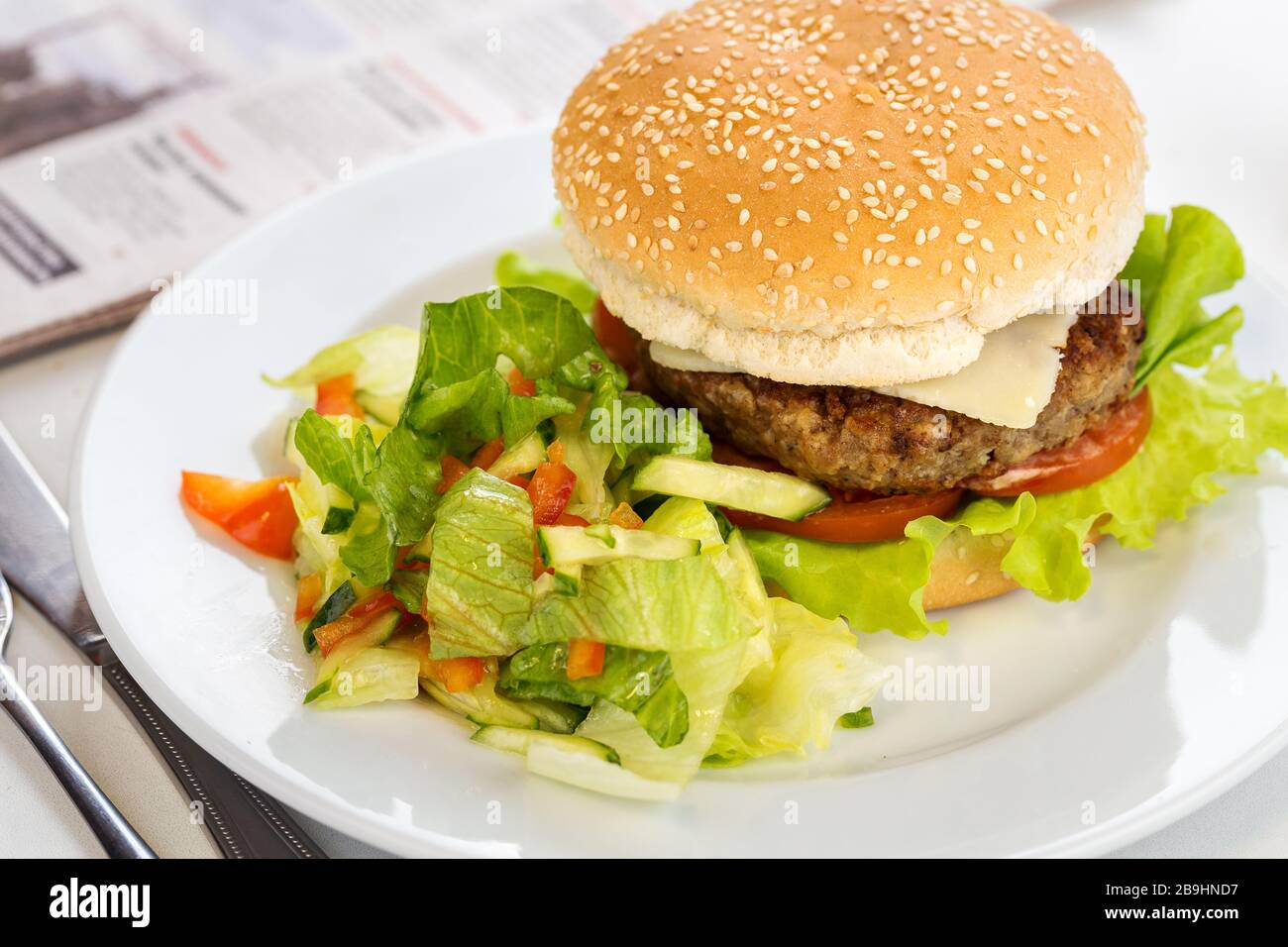 Délicieux hamburger de bœuf grillé sur une assiette avec garniture de salade Banque D'Images