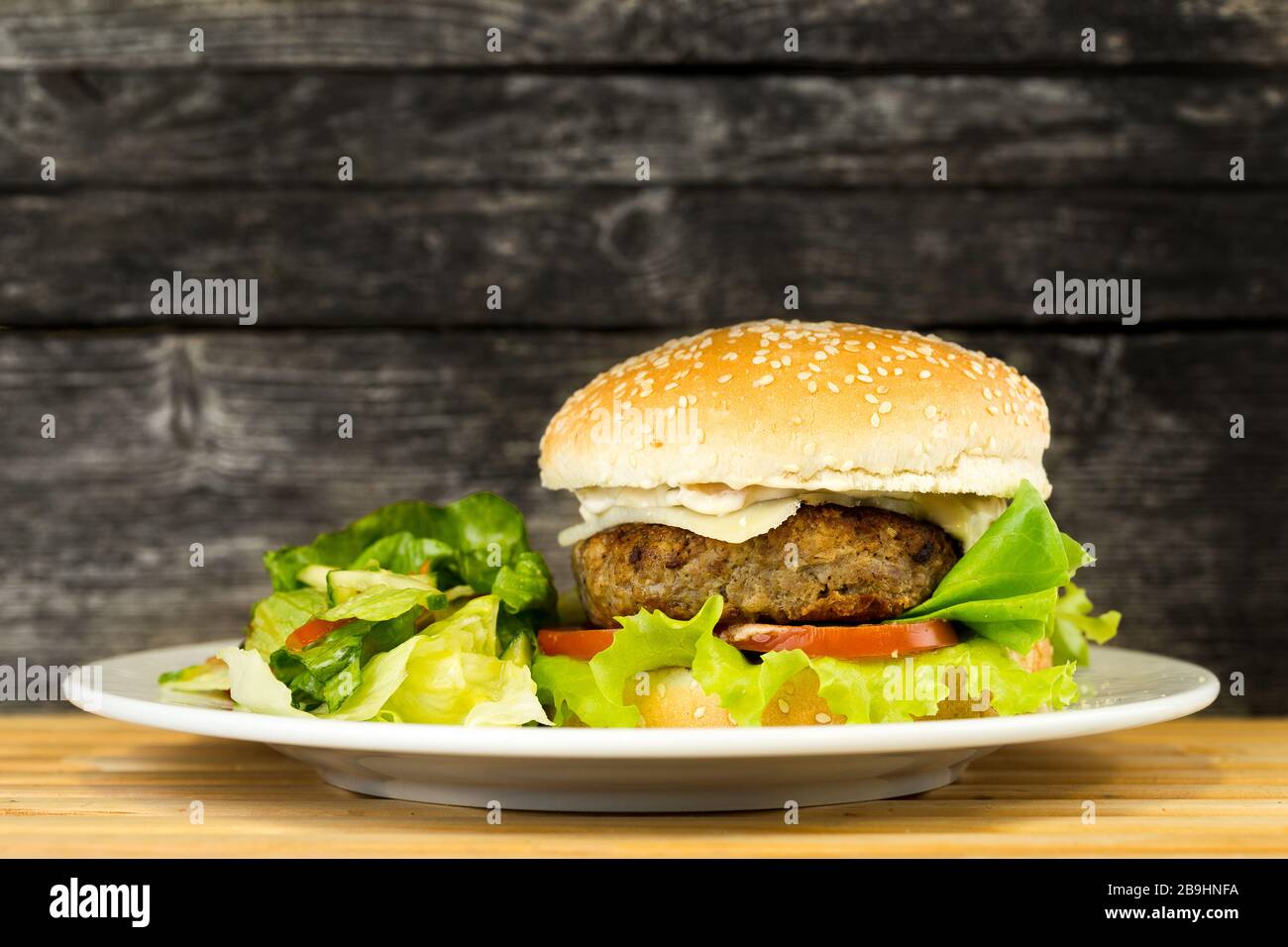 Hamburger de bœuf grillé Delicous sur fond rustique servi avec salade sur une plaque avec espace de copie Banque D'Images